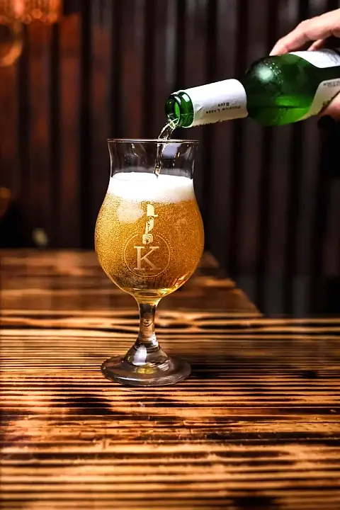 Craft beer poured into a Klandestino glass on the wooden bar
