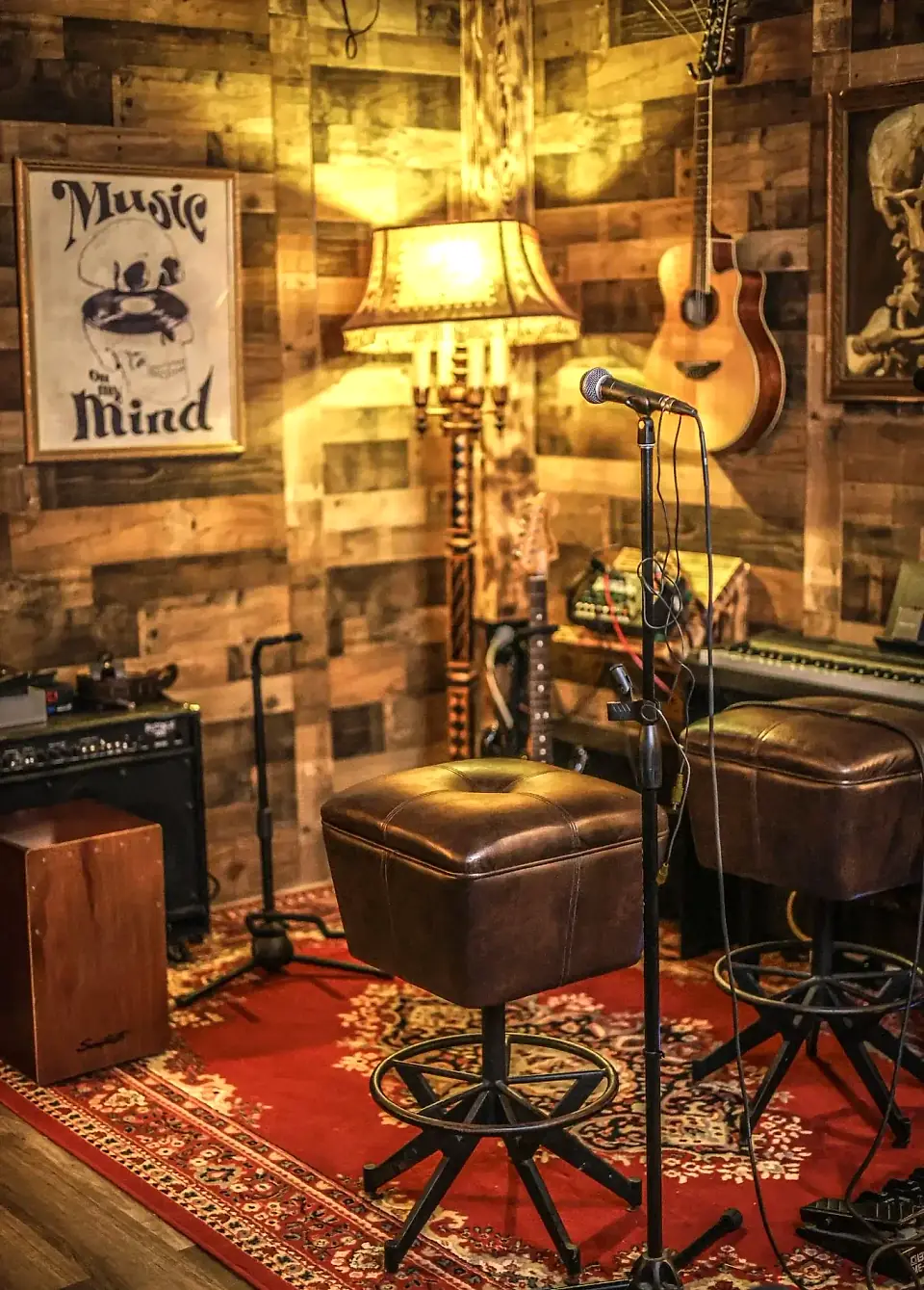 The live music stage at Klandestino Lounge in North Miami: microphone, guitar, keyboard and leather stools on a red rug
